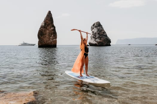 Close up shot of beautiful young caucasian woman with black hair and freckles looking at camera and smiling. Cute woman portrait in a pink bikini posing on a volcanic rock high above the sea