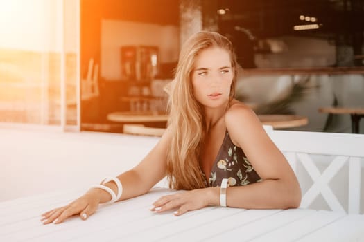 Happy woman portrait in cafe. Boho chic fashion style. Outdoor photo of young happy woman with long hair, sunny weather outdoors sitting in modern cafe