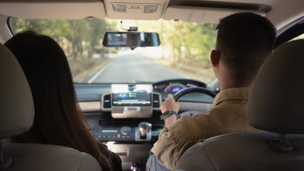 Rear view of couple having fun together driving by countryside. Road trip, traveling and lifestyle concept.