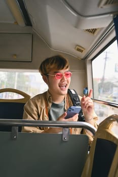 Young stylish man text messaging on smart phone, traveling by bus. Public transportation concept.
