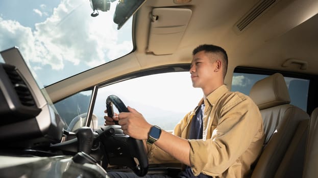 Handsome millennial man driving car, enjoying road trip on vacation. Transport, summer vacation and holiday.