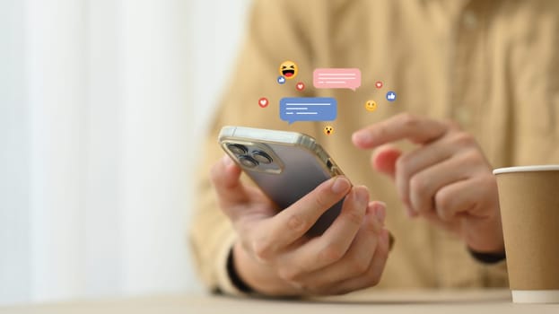 Young woman using mobile phone with likes, emoji icons while sharing or commenting in online community.