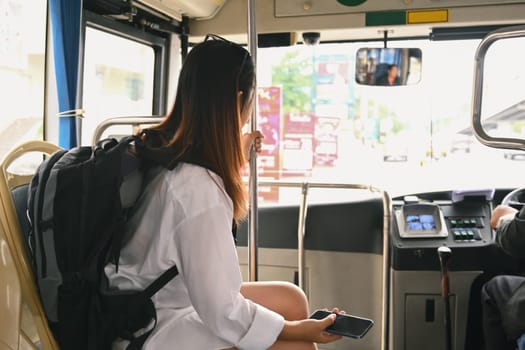 Female traveler with backpack sitting in public transportation. Travel lifestyle and transportation concept.