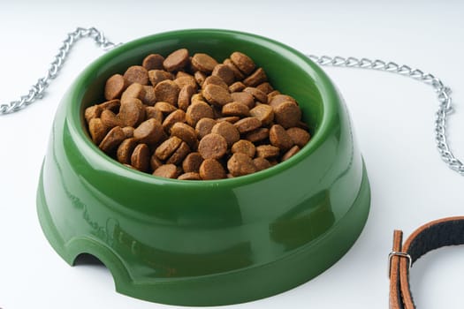 Green plastic bowl with dry pet food isolated on white background