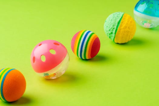 Colorful pet toys balls on green background close up