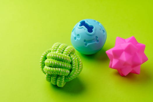 Colorful pet toys balls on green background close up