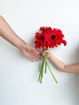 small child gives his father bouquet of flowers on white background. Fathers Day. holiday card concept with place for text