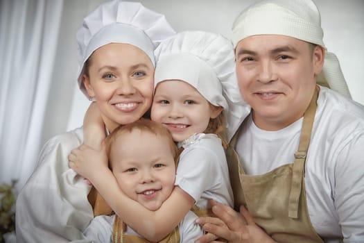 Cute oriental family with mother, father, daughter, son cooking in kitchen on Ramadan, Kurban-Bairam, Eid al-Adha. Funny family at a cook photo shoot. Pancakes, pastries, Maslenitsa, Easter