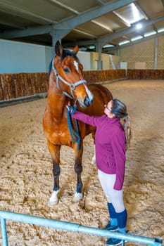 Vertical portrait of a woman with a race horse in a training area
