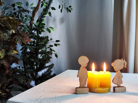 Wooden toys of boy and girl with yellow candles. Couple in love on Valentine's Day. Celebration of love and friendship. Card, background