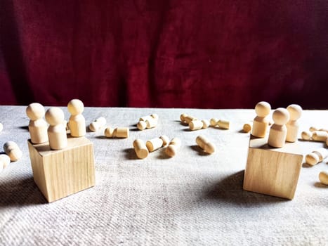 Wooden toys stand opposite and lot of lying figures. Concept of dispute between leaders of two groups. Government and deaths of citizens and soldiers. War in Russia, Ukraine, Israel, Palestine