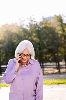 senior woman smiling happy talking by mobile phone outdoors, concept of technology and elderly people leisure, copy space for text