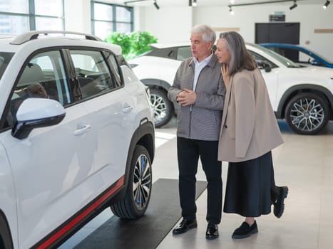 An elderly Caucasian couple chooses a new car at a car dealership