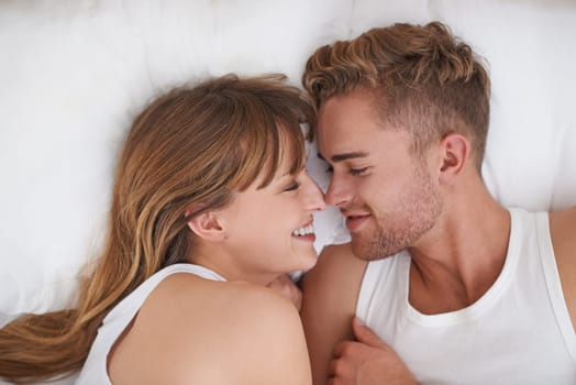 Couple, love and relaxing in bed on weekend, happy and bonding or care in relationship at home. People, loyalty and commitment to marriage in bedroom, smiling and romance or comfortable and lazy.