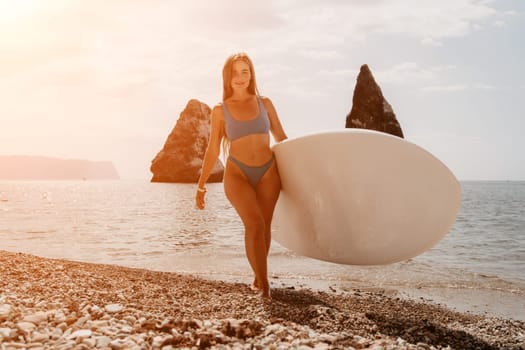 Close up shot of beautiful young caucasian woman with black hair and freckles looking at camera and smiling. Cute woman portrait in a pink bikini posing on a volcanic rock high above the sea