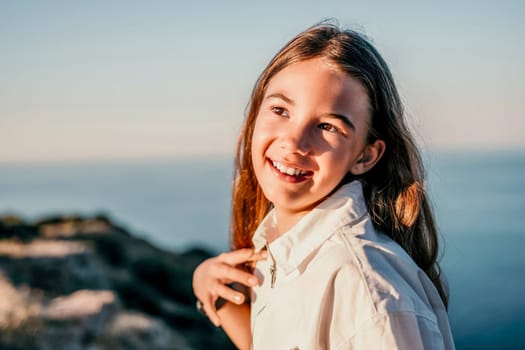 Brown-haired young romantic teenager girl corrects long hair on beach at summer evening wind