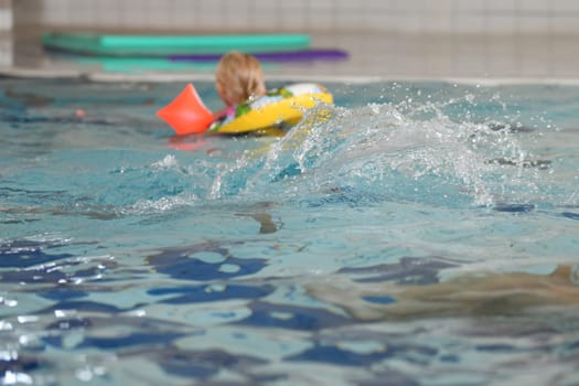 Children playing in the pool with sleeves and inflatable ring