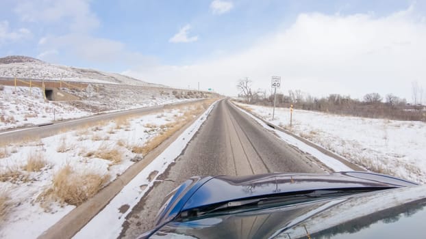 Navigating a frontage road post-winter storm offers a serene drive. The surrounding landscape, blanketed in snow, contributes to the peaceful and picturesque environment, enhancing the driving experience.