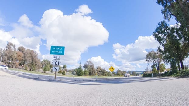 Santa Maria, California, USA-December 6, 2022-On a clear winter day, a car smoothly travels along Highway 101 near Santa Maria, California, under a brilliant blue sky, surrounded by a blend of greenery and golden hues.