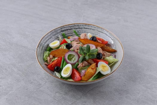 salad with tuna, quail eggs and baked potatoes on a stone background, studio food photography