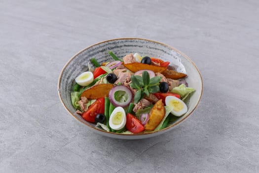 salad with tuna, quail eggs and baked potatoes on a stone background, studio food photography 2