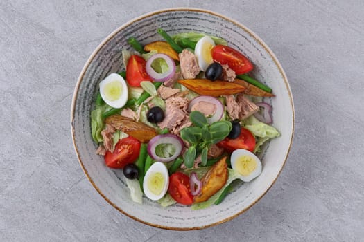 salad with tuna, quail eggs and baked potatoes on a stone background, studio food photography 1