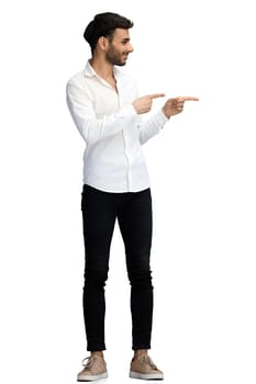 A young man on a white background in full growth shows his hand to the side.