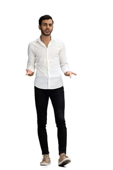 A young man on a white background in full growth spreads his arms to the sides, in profile.
