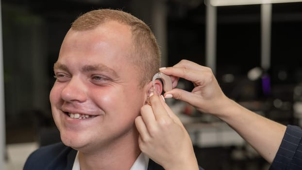 Woman putting hearing aid on Caucasian man