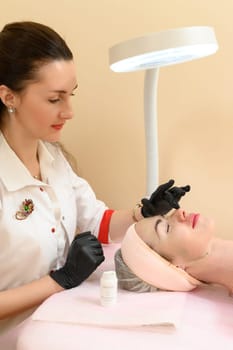 Ivano-Frankivsk, Ukraine May 17, 2023: Rubbing the cream with massage movements on the face, therapy at a cosmetologist, cosmetology procedure carboxytherapy