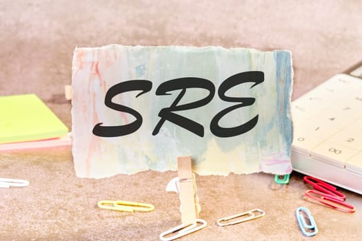 SRE. Site Reliability Engineering text on a piece of paper on the table with a clothespin clamped