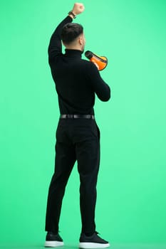 A man, on a green background, in full height, with a megaphone.
