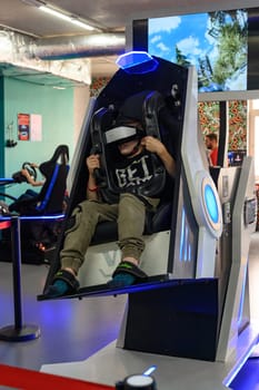 Ivano-Frankivsk, Ukraine June 7, 2023:Happy reactions in a child from an attraction with a virtual reaction, virtual reality glasses and children's entertainment.