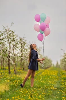 girl with balloons in a young blooming garden