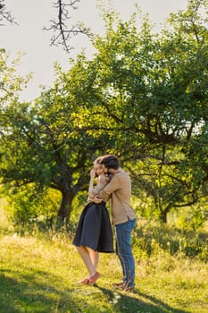 young couple, illuminated by the backlit sun, hugging in nature