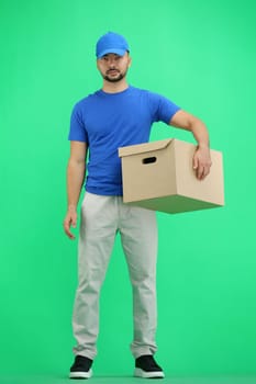 The deliveryman, full-length, on a green background, with a box.