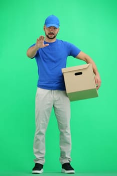 The deliveryman, in full height, on a green background, with a box, shows a stop sign.
