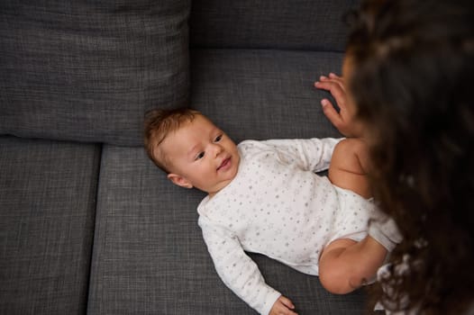 Young mother nursing her adorable smiling baby. First emotions and kids facial expressions in babyhood. View from above. People Lifestyle Maternity Infancy Motherhood