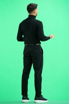 A man, full-length, on a green background, spreads his arms.
