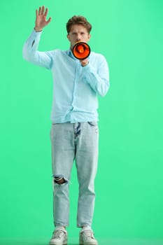 A man, on a green background, in full height, with a megaphone.