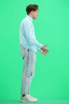 A man, full-length, on a green background, spreads his arms.