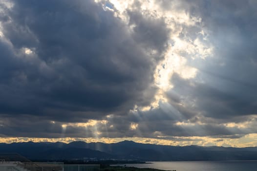 sun rays through dramatic clouds over mountains and sea in cyprus