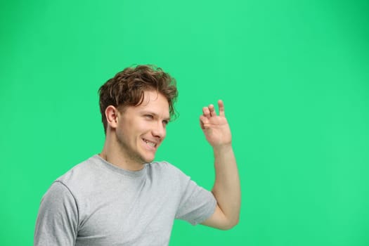 A man, on a green background, in close-up, shows an ok sign.