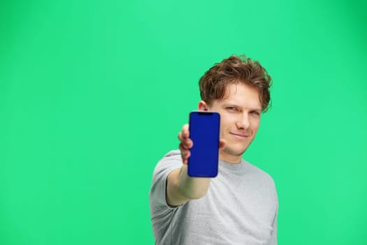 Man, on a green background, close-up, with a phone.