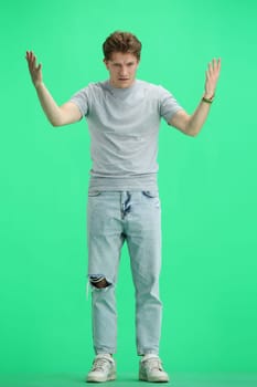 A man, full-length, on a green background, spreads his arms.
