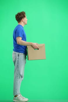 The deliveryman, full-length, on a green background, with a box.