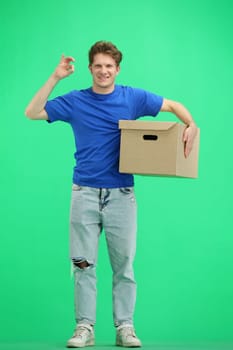 The deliveryman, in full height, on a green background, with a box, shows the ok sign.