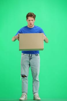 The deliveryman, full-length, on a green background, with a box.