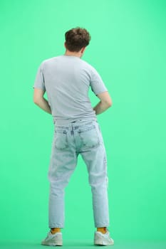 A man, full-length, on a green background, dancing.