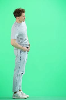 A man, full-length, on a green background.